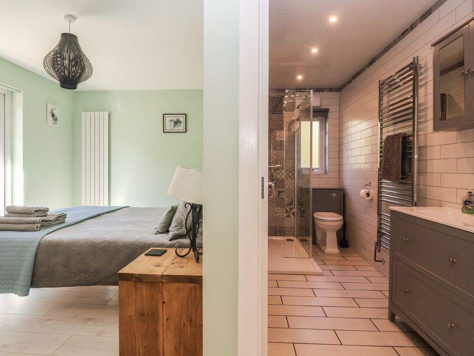 A bedroom with a bed and a bathroom with a shower at Bluebell Wood in Brandesburton