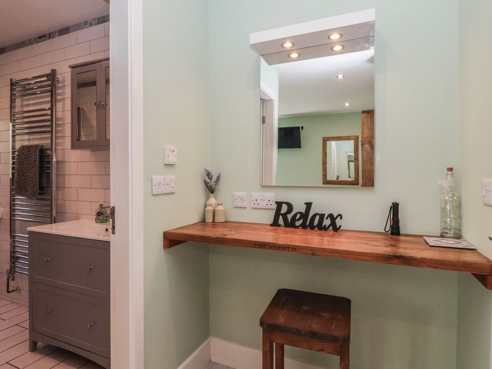A bathroom with a mirror and wooden shelf at Bluebell Wood in Brandesburton