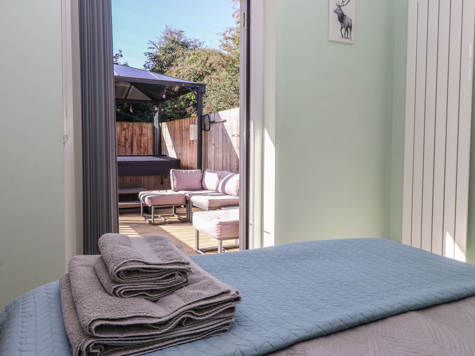 A bedroom with towels and a view of a seating area and hot tub at Bluebell Wood in Brandesburton