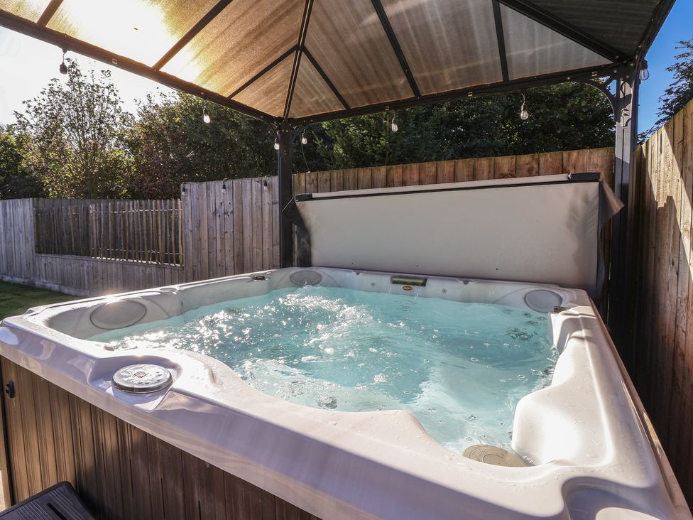 A hot tub under a canopy in a garden at Bluebell Wood in Brandesburton