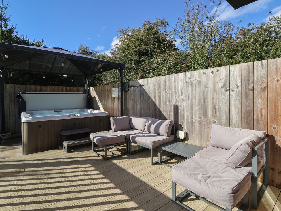 An outdoor area with a hot tub and seating at Bluebell Wood in Brandesburton