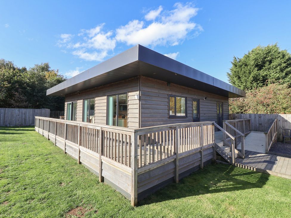 A wooden house with deck and grass area at Bluebell Wood in Brandesburton