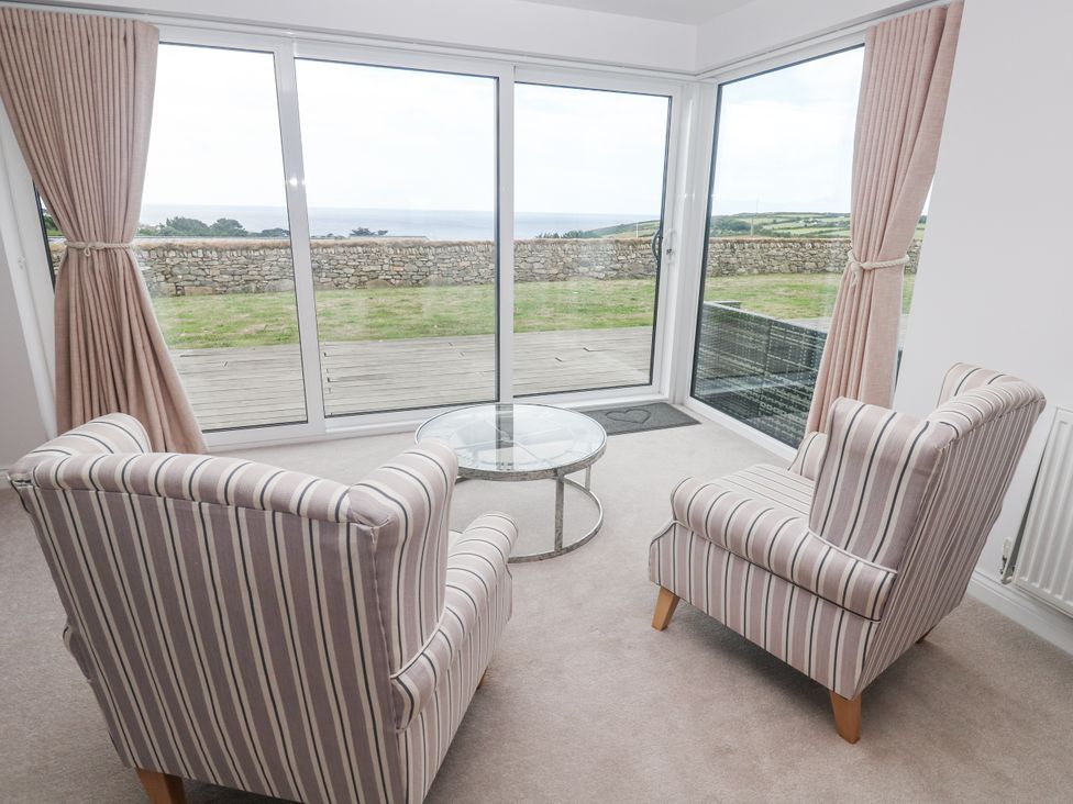 A living room with two chairs and a glass table at Atlantic View in Germoe