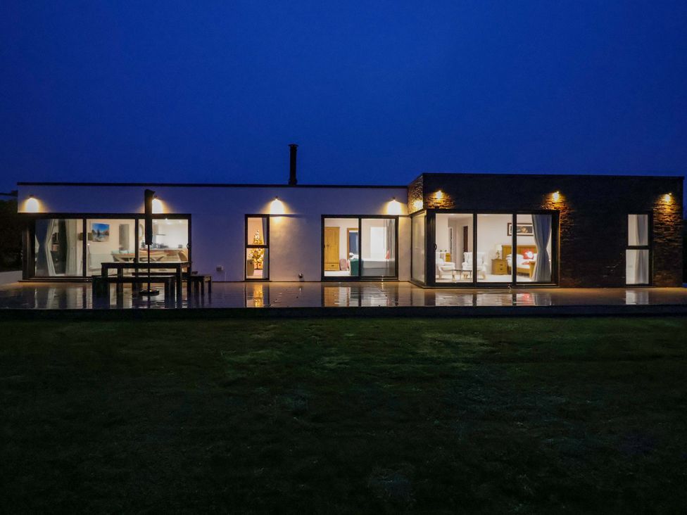 An external view of a house with illuminated windows at Atlantic View in Germoe