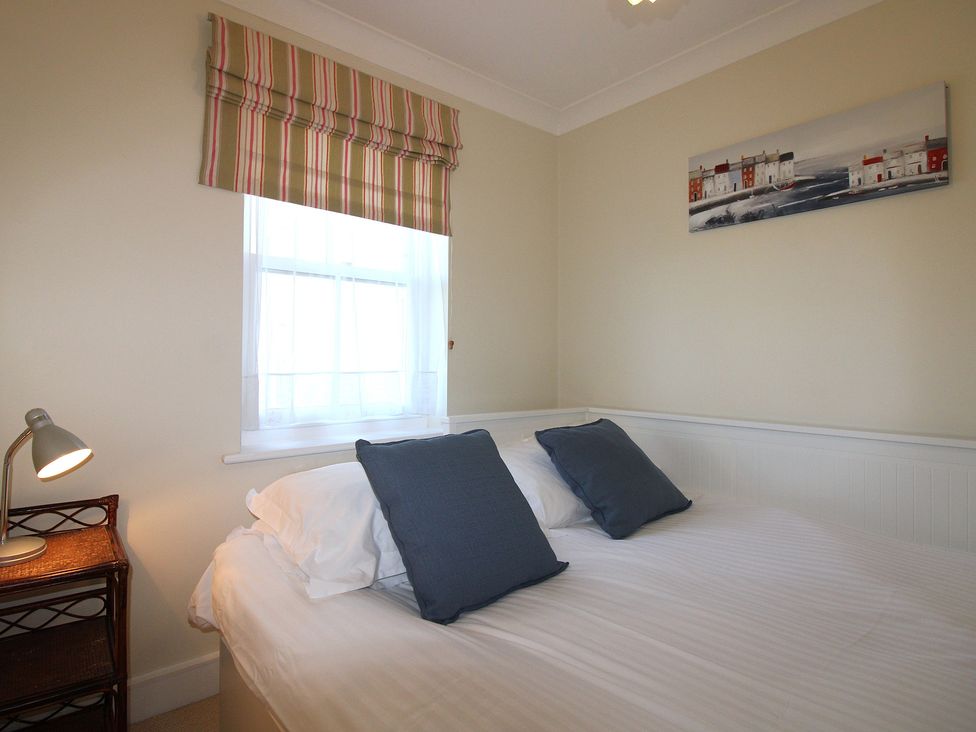 A bedroom with a bed and a lamp at 4 Thurlestone Beach House South Milton near Thurlestone
