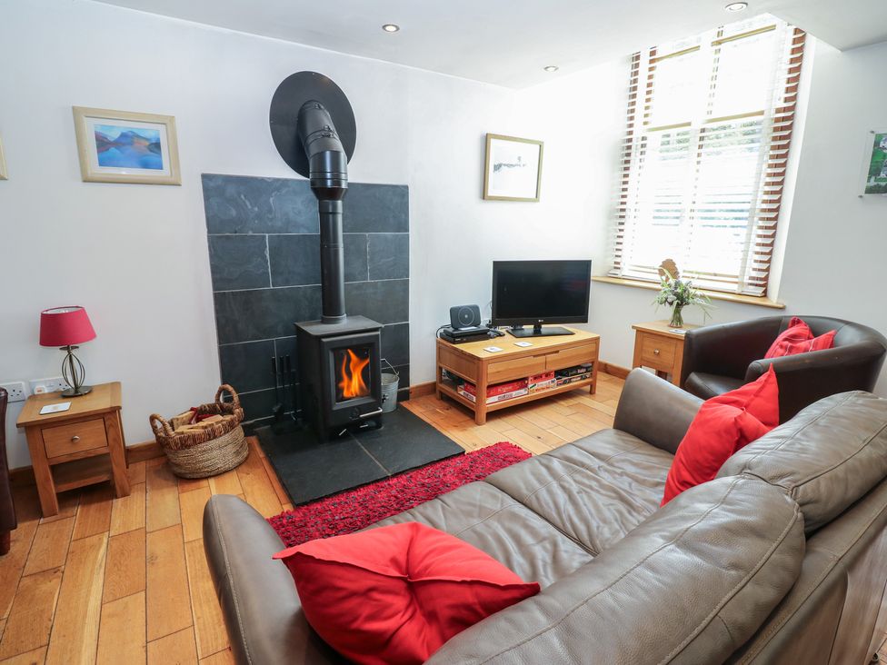 A living room with a stove and sofa at Chapel Cottage Sandford, Cumbria
