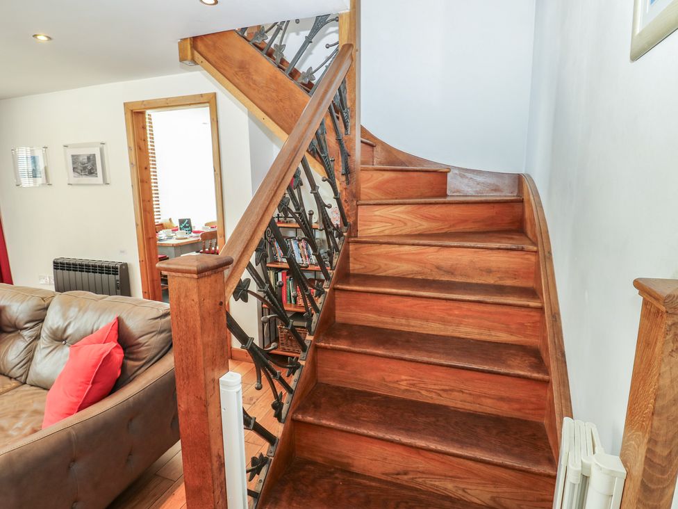 A staircase leading to the upper floor with a sofa in the living room at Chapel Cottage in Sandford, Cumbria