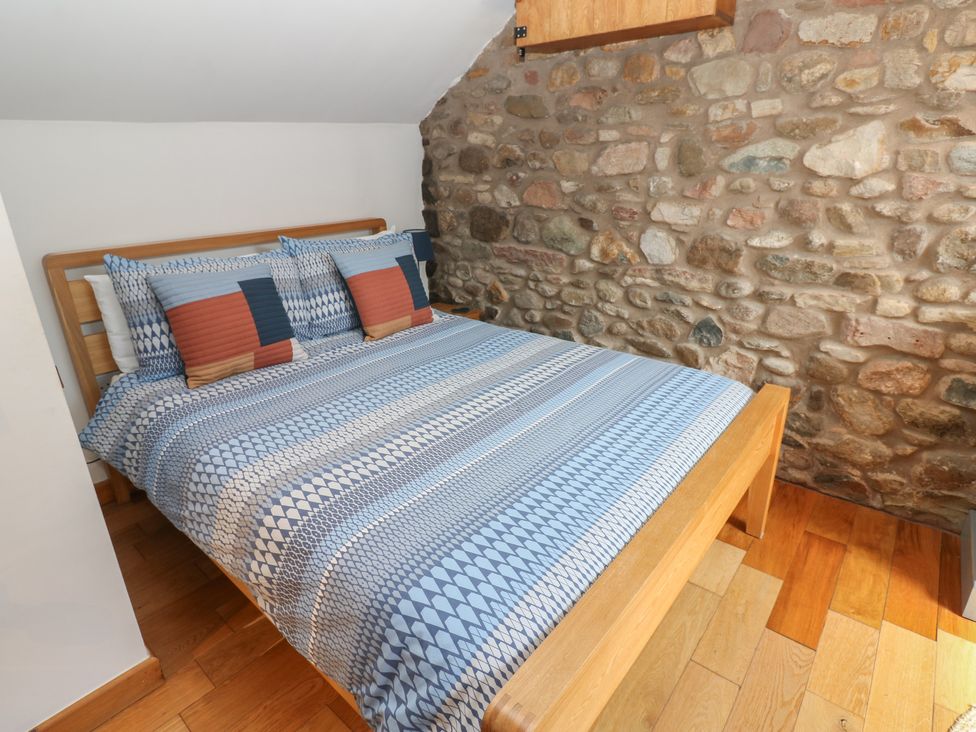 A bedroom with a bed and stone wall at Chapel Cottage in Sandford, Cumbria