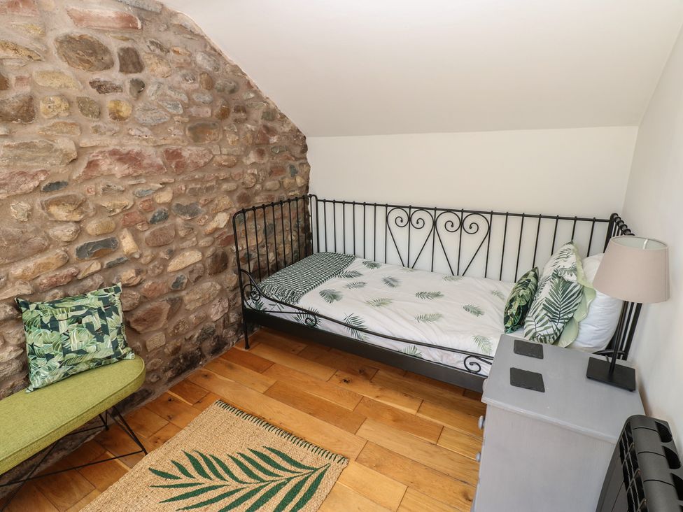A bedroom with a bed and chair at Chapel Cottage in Sandford, Cumbria