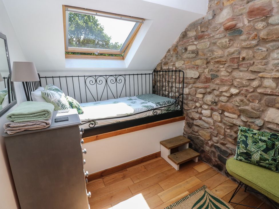 A bedroom with a bed and a green chair at Chapel Cottage in Sandford, Cumbria