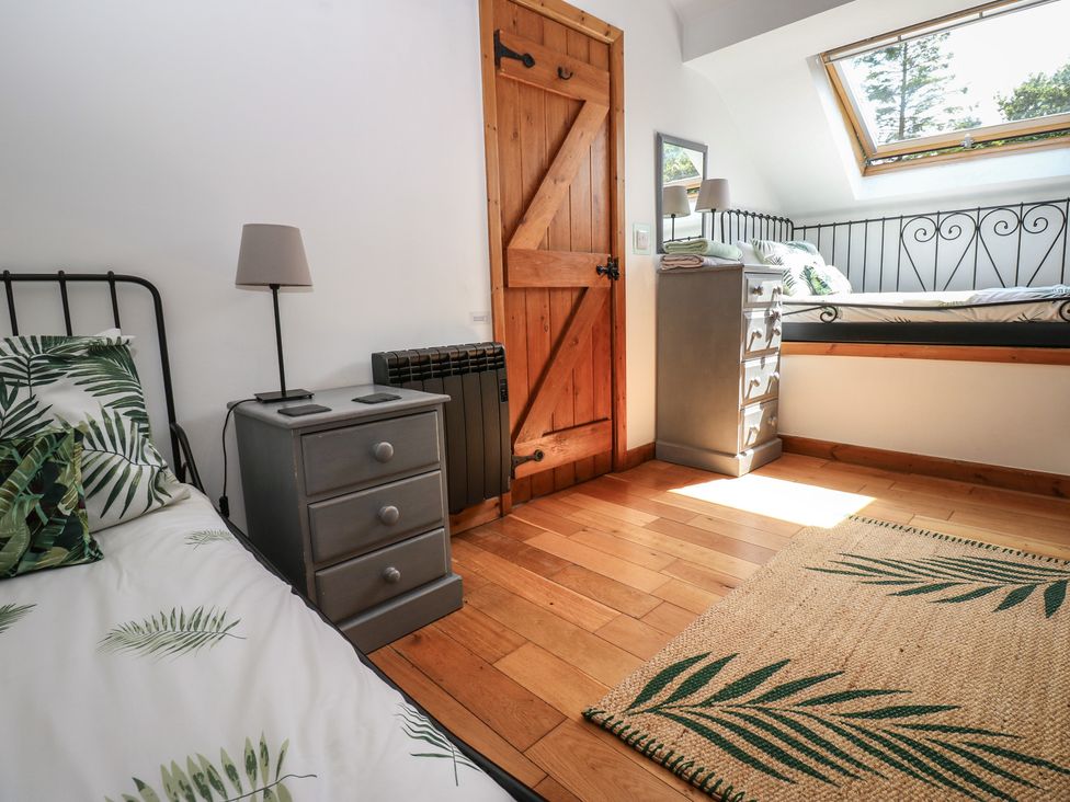 A bedroom with a bed, nightstand, and window at Chapel Cottage Sandford, Cumbria