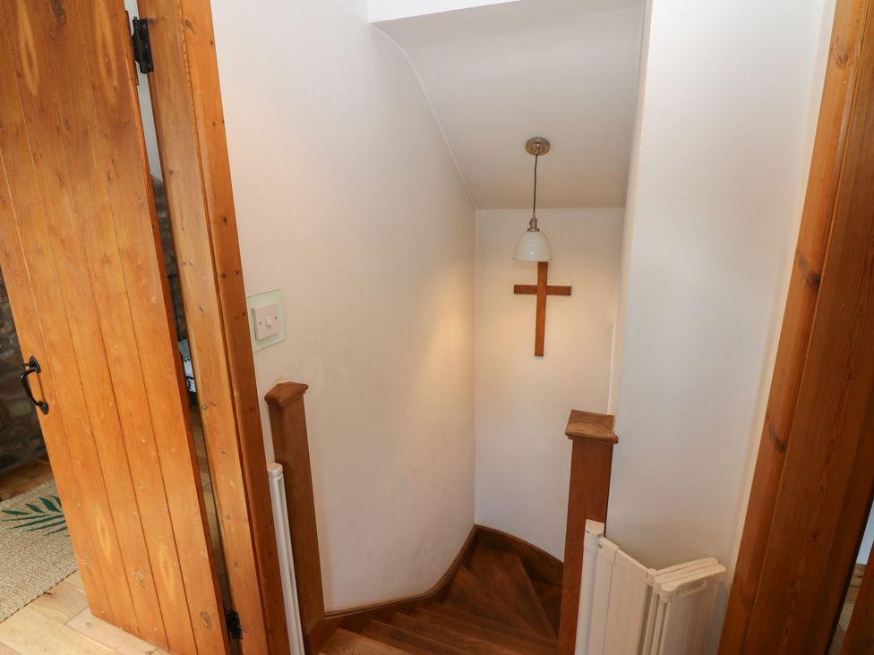 A staircase with a lamp and cross at Chapel Cottage in Sandford, Cumbria
