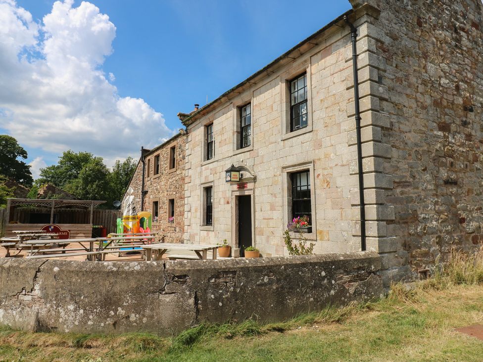 An outdoor view of a stone building with a seating area at Chapel Cottage Sandford, Cumbria