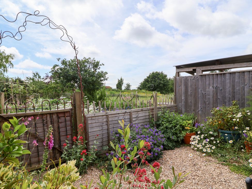 A garden with flowers and an archway at Tiny Willow in Farrington near Child Okeford