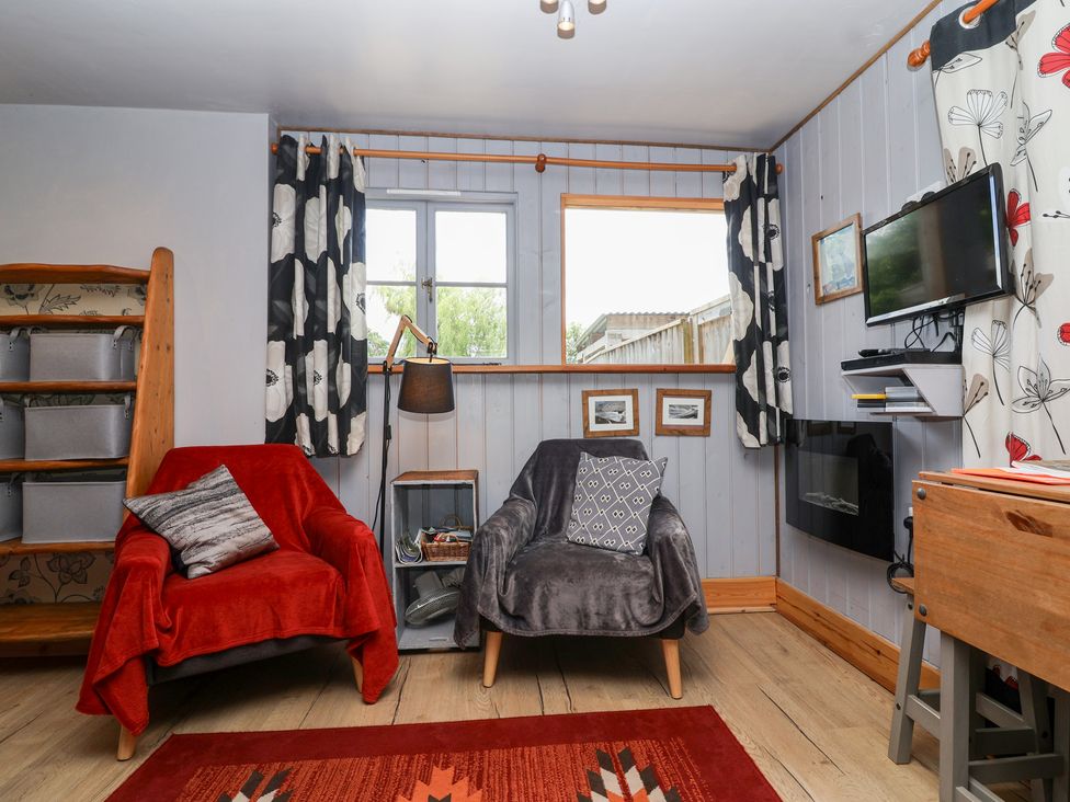 A living room with two armchairs and a shelf at Tiny Willow in Farrington near Child Okeford