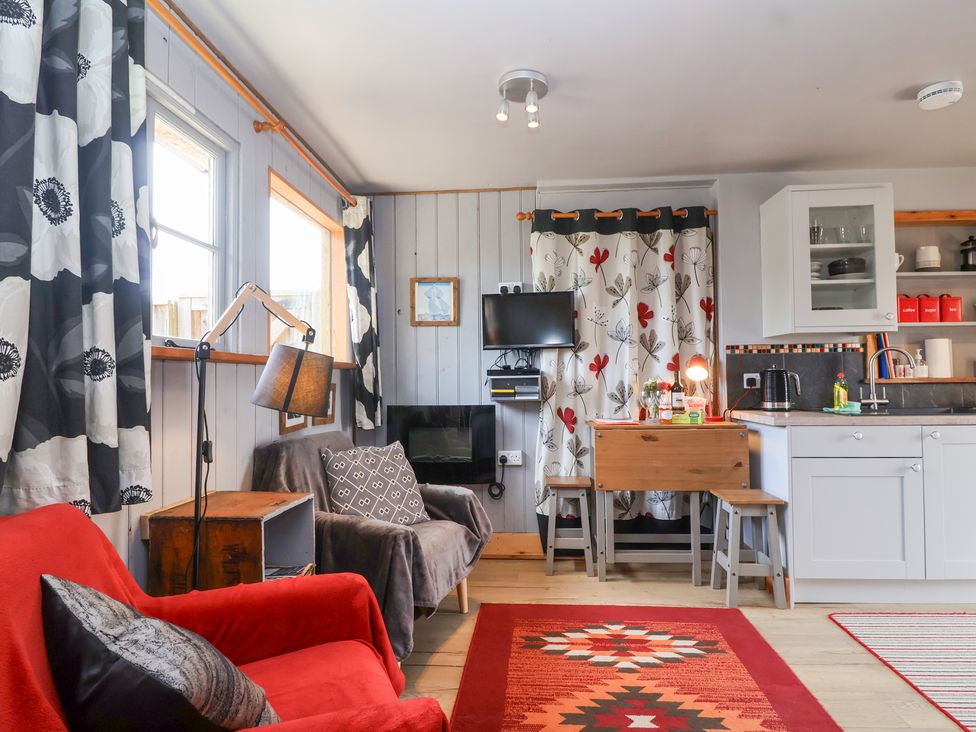 A living room with a sofa and a kitchen area at Tiny Willow in Farrington near Child Okeford