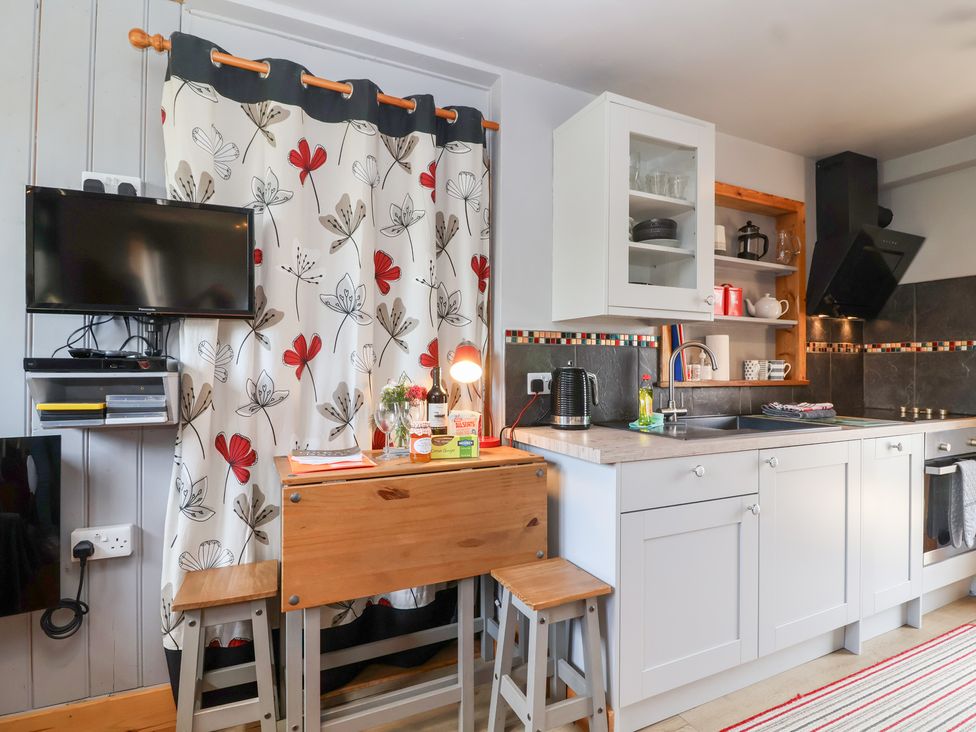 A kitchen with a table and stools at Tiny Willow in Farrington near Child Okeford
