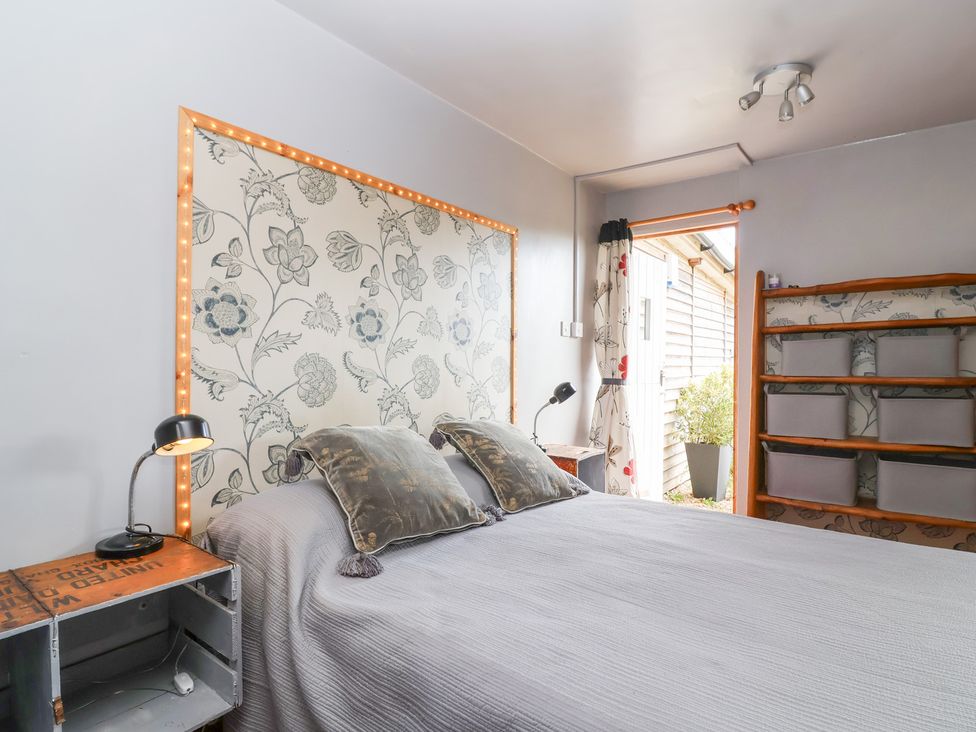 A bedroom with a bed and shelves at Tiny Willow in Farrington near Child Okeford