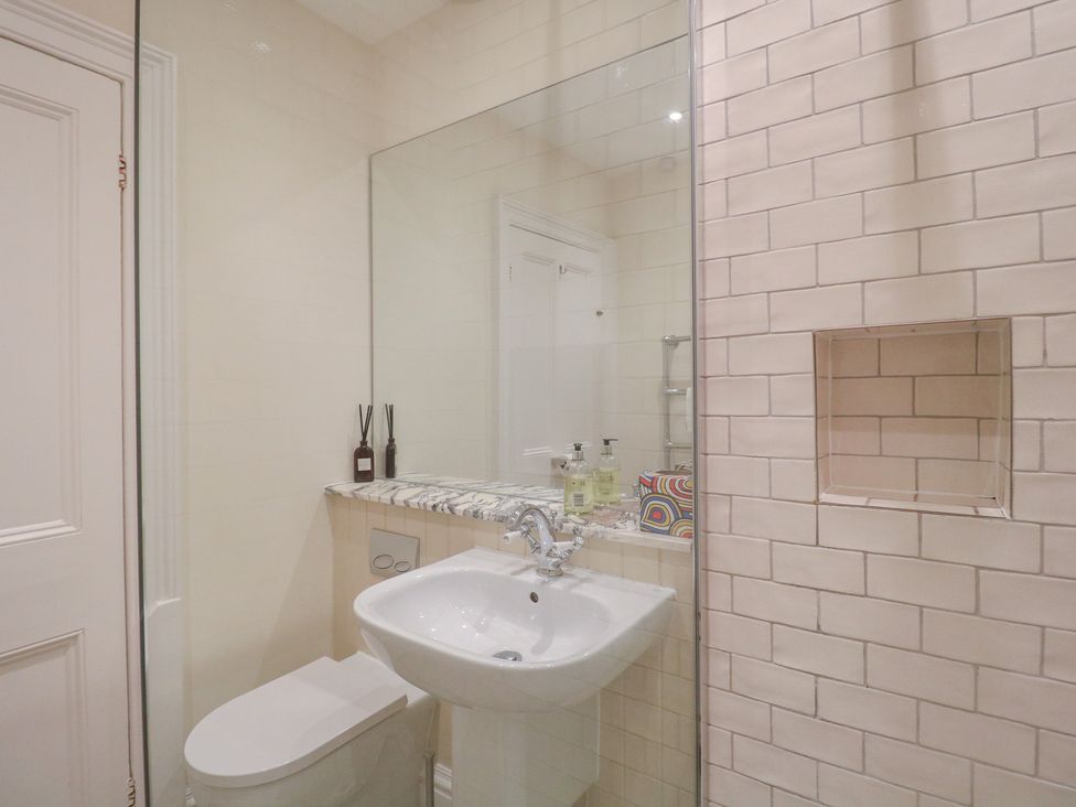 A bathroom with a sink, toilet, and mirror at 2 York House in Dartmouth