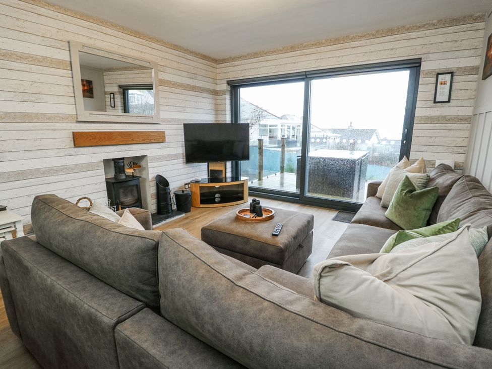 A living room with a sofa, television, and fireplace at Daisy Cottage in Benllech
