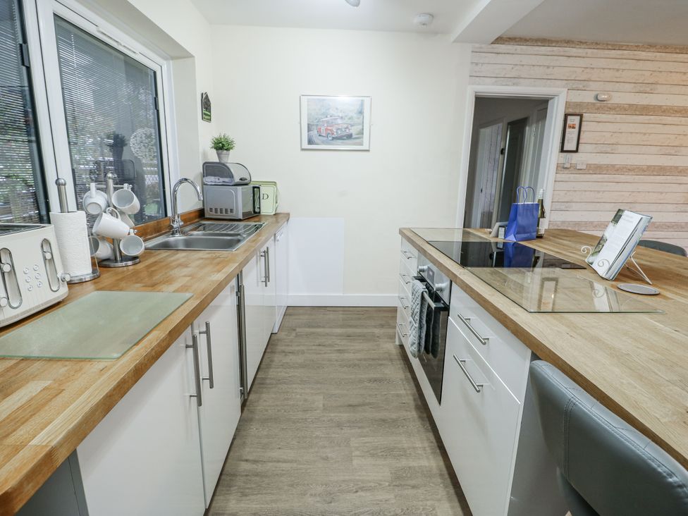 A kitchen with a sink and cooking appliances at Daisy Cottage in Benllech