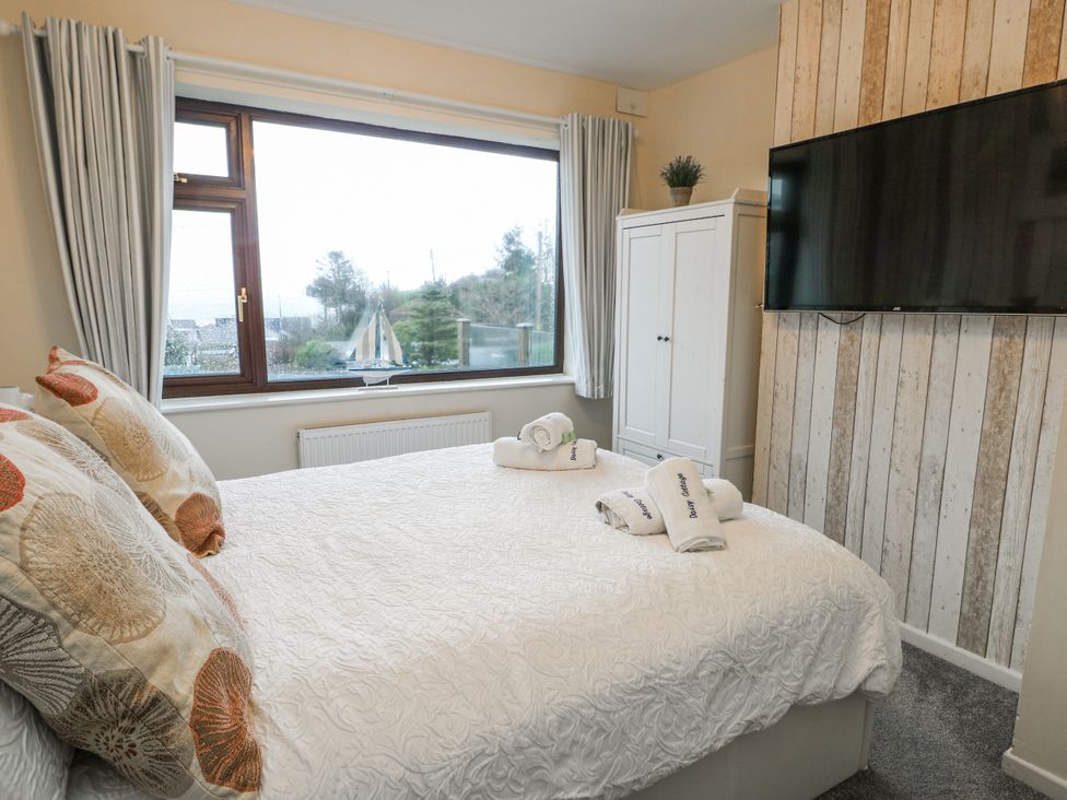 A bedroom with a bed and a television at Daisy Cottage Benllech