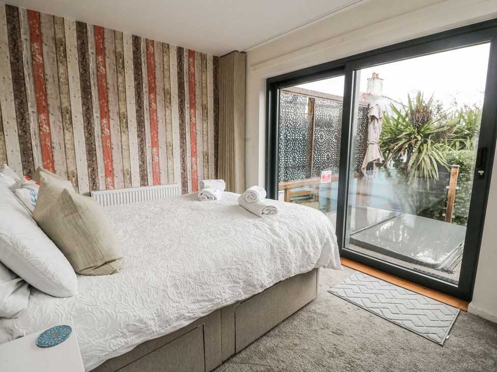 A bedroom with a bed and sliding door leading outside at Daisy Cottage in Benllech