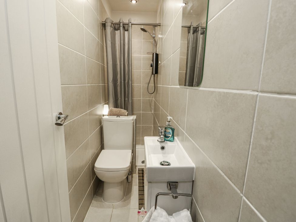 A bathroom with a toilet and a wash basin at Daisy Cottage Benllech