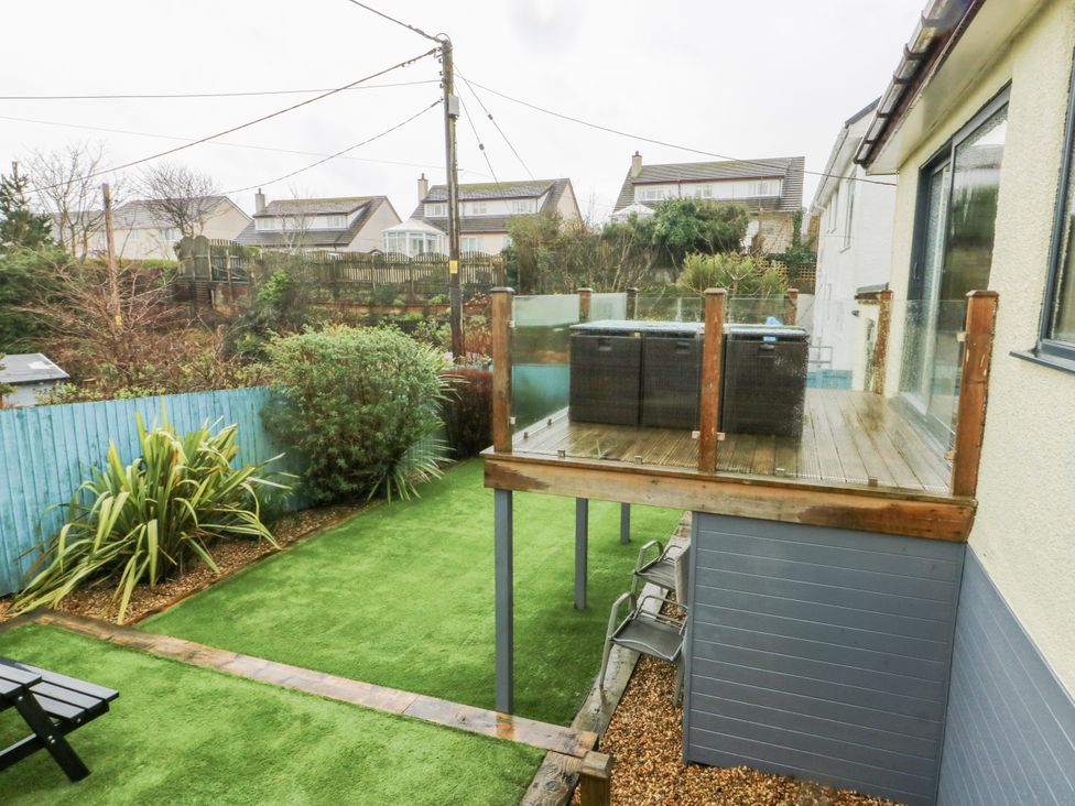 A garden with a deck and hot tub at Daisy Cottage in Benllech