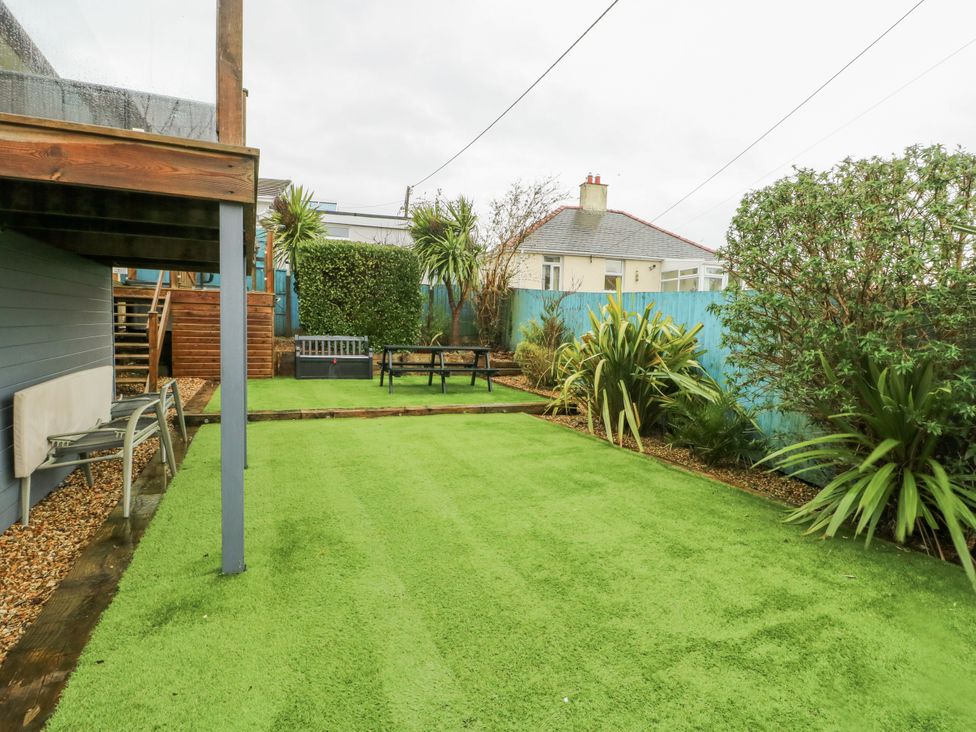 A garden with artificial grass and seating at Daisy Cottage Benllech
