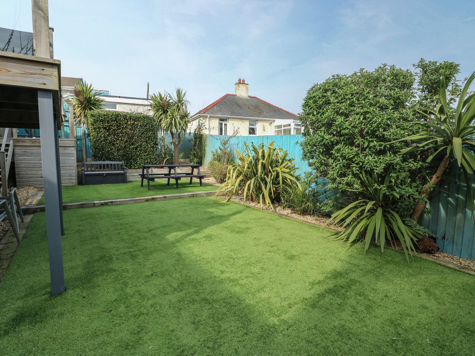 A garden with artificial grass and seating area at Daisy Cottage in Benllech