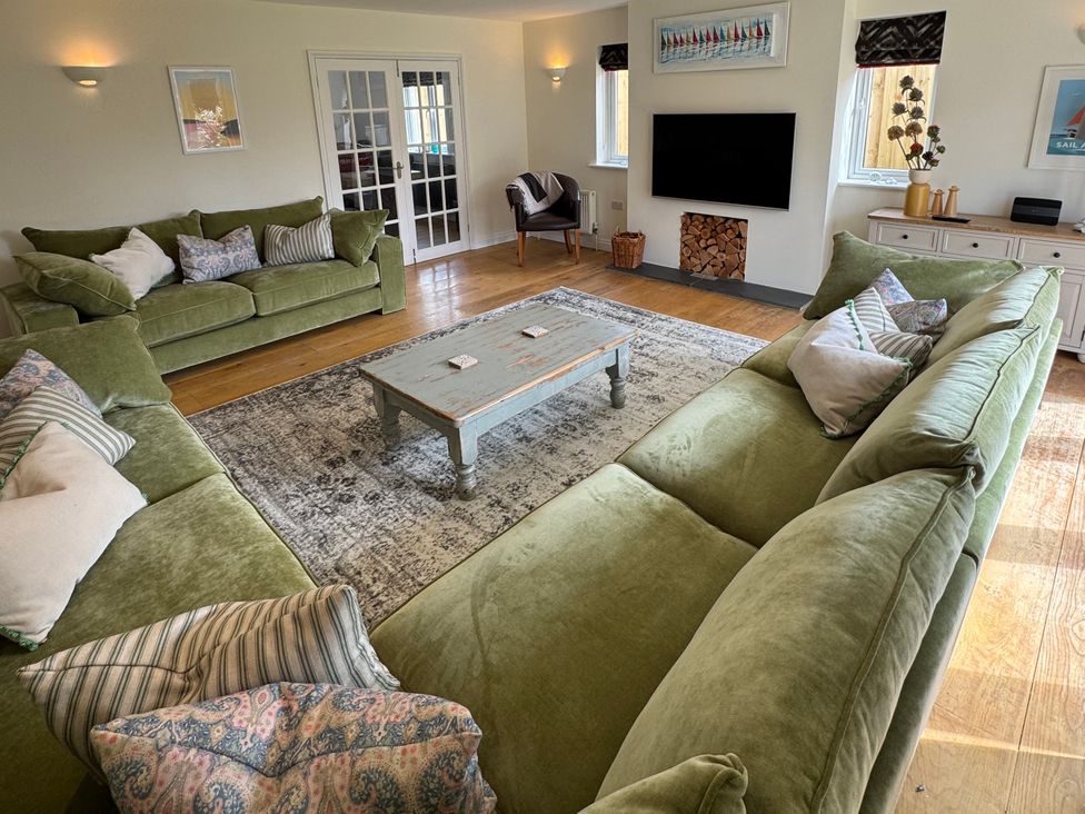 A living room with green sofas and a coffee table at Trevose House in Crantock