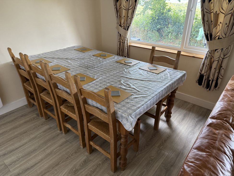 A dining table with wooden chairs and tablecloth at Hembry Meadows Honicombe Park near Gunnislake