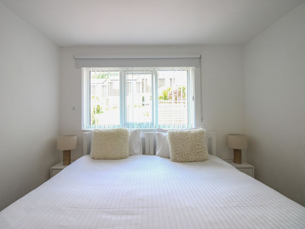 A bedroom with a bed, nightstands, and a window at Little Starboard in Kingsbridge