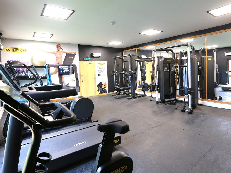 A gym with exercise equipment and mirrors at Honeybee Cottage in Penruddock