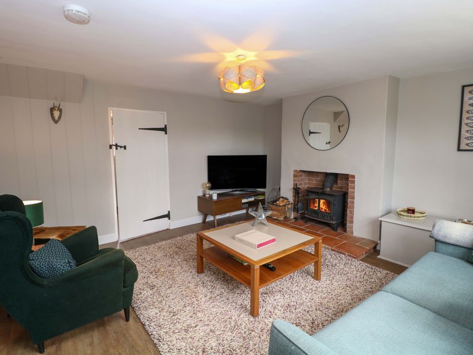 A living room with a fireplace and television at The Mallows in Walsingham