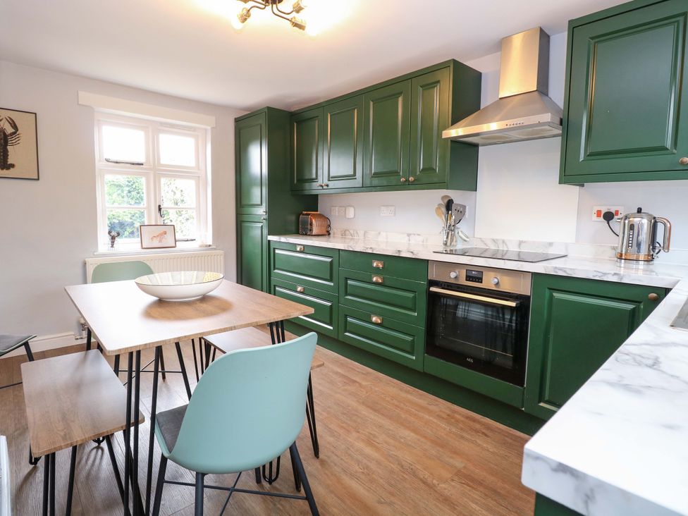 A kitchen with green cabinets and a dining table at The Mallows in Walsingham