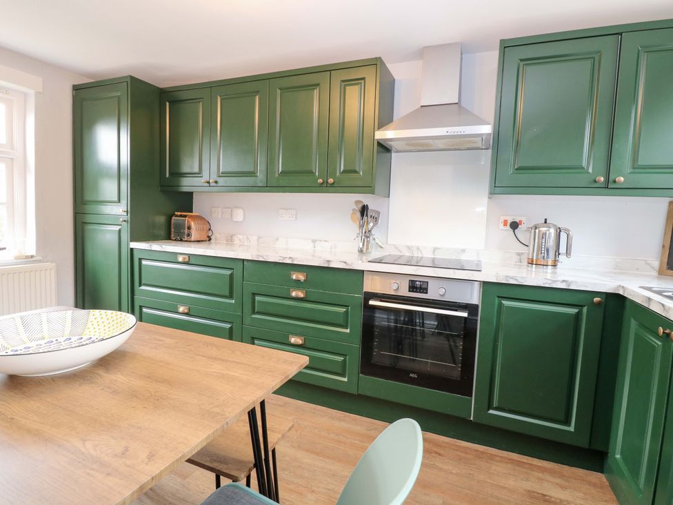 A kitchen with green cabinets and appliances at The Mallows in Walsingham