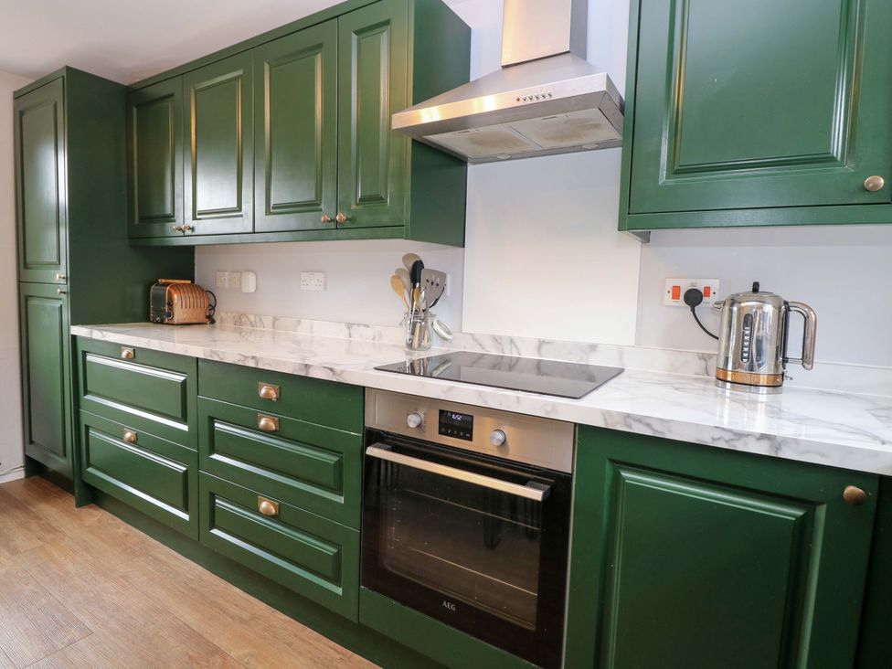 A kitchen with green cabinets and a cooking area at The Mallows in Walsingham