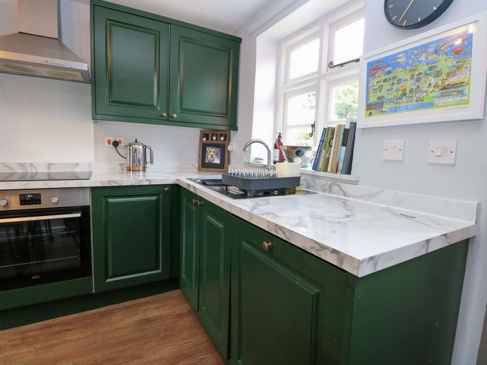 A kitchen with green cabinets and marble countertop at The Mallows in Walsingham