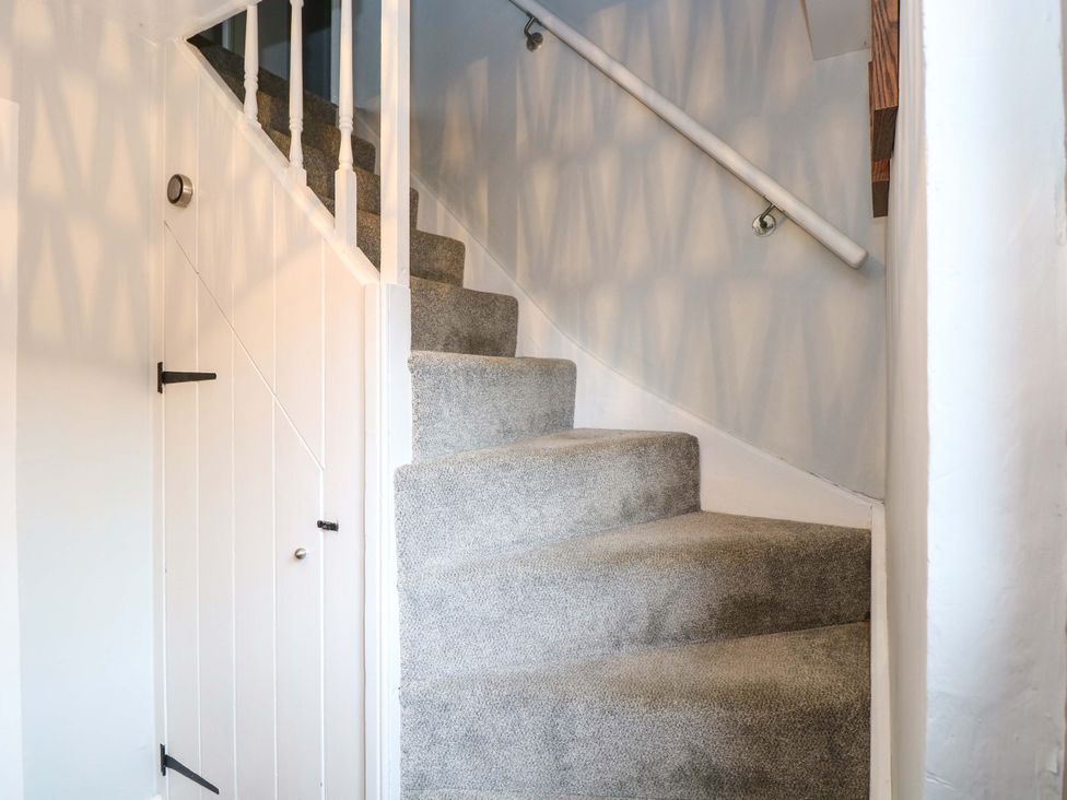 A staircase with grey carpet and a door at The Mallows in Walsingham