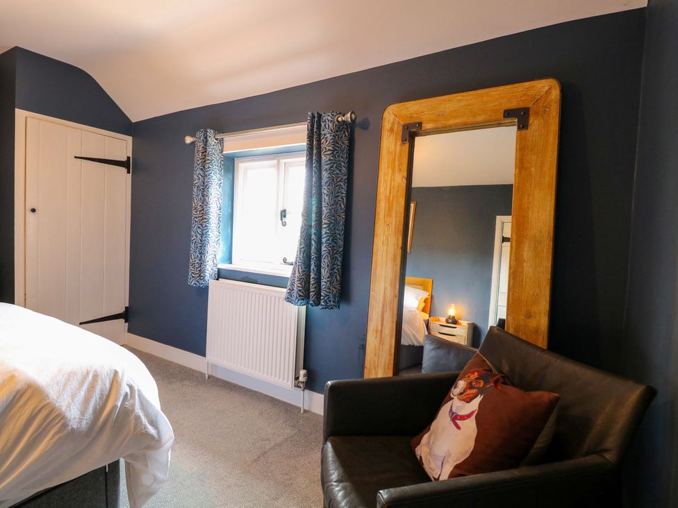 A bedroom with a bed, mirror and window at The Mallows in Walsingham
