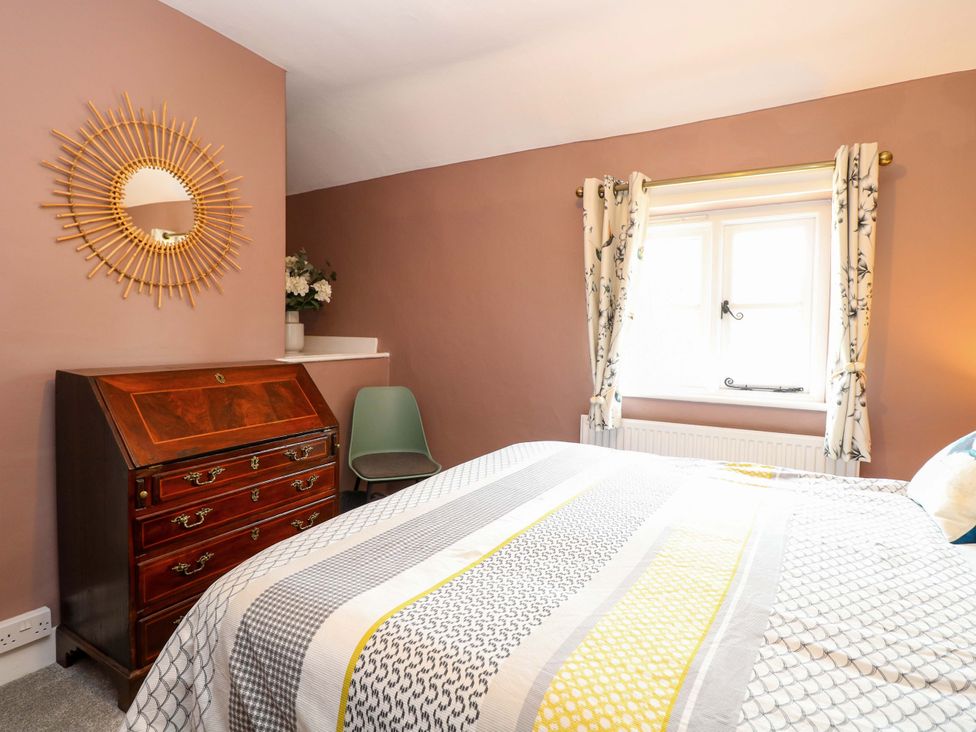 A bedroom with a bed, mirror, and window at The Mallows in Walsingham