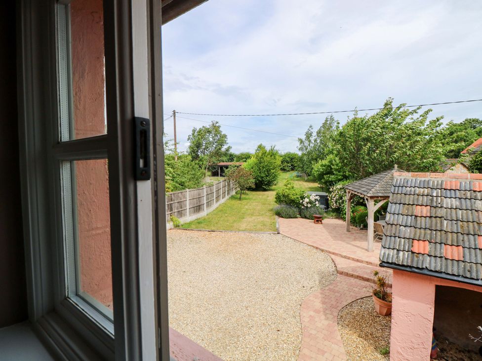 A view of a garden with a fence and a shed at The Mallows in Walsingham