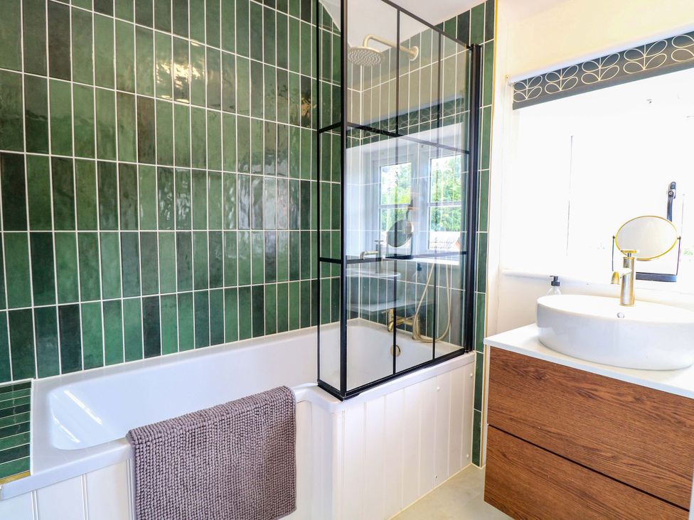 A bathroom featuring a bathtub, glass shower, sink and mirror at The Mallows in Walsingham