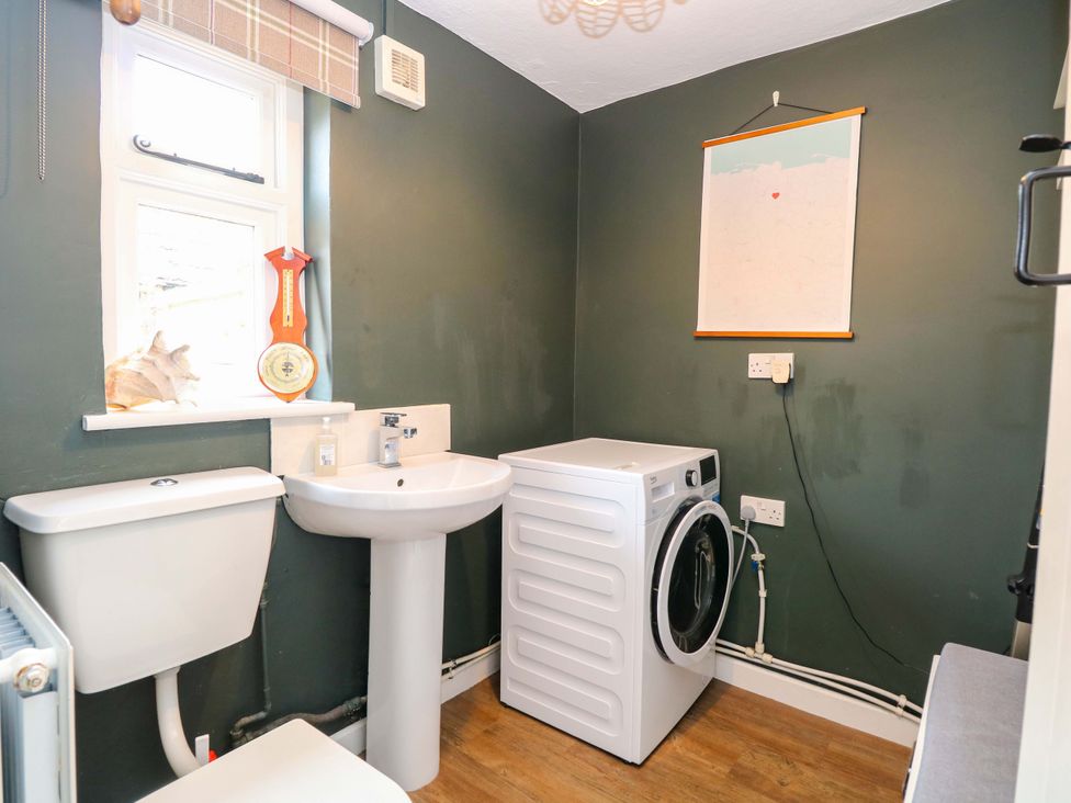 A utility room with a washing machine and sink at The Mallows in Walsingham