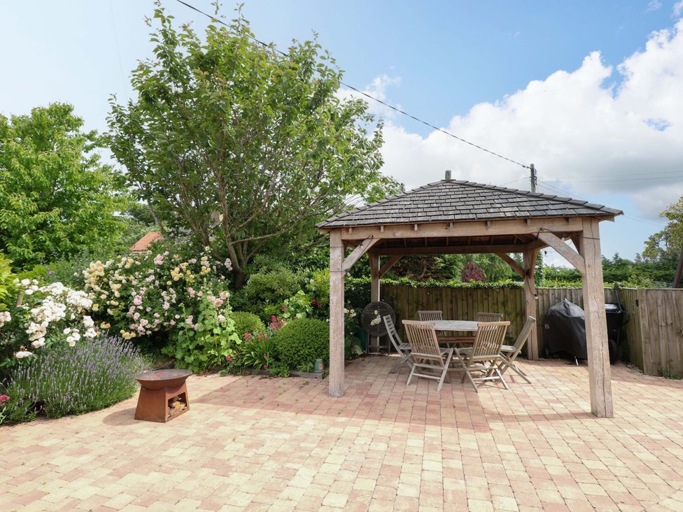 A garden with a gazebo and seating area at The Mallows in Walsingham