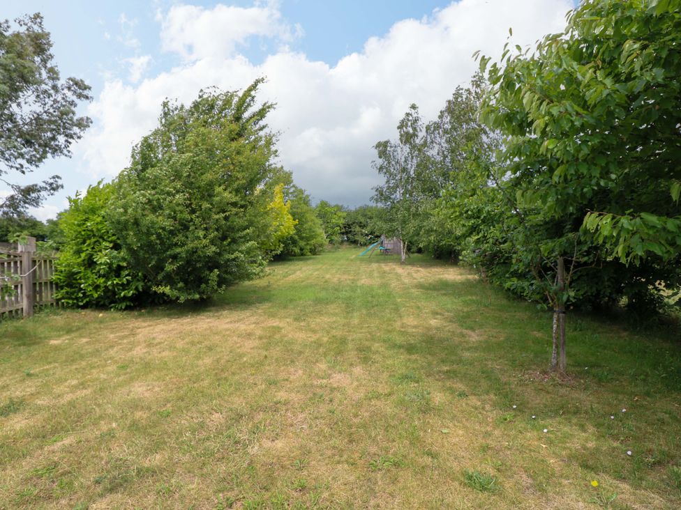 A garden with trees and play equipment at The Mallows in Walsingham