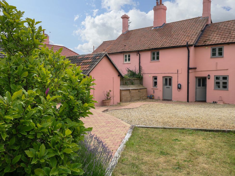 An outdoor view of a pink house with a garden pathway at The Mallows in Walsingham