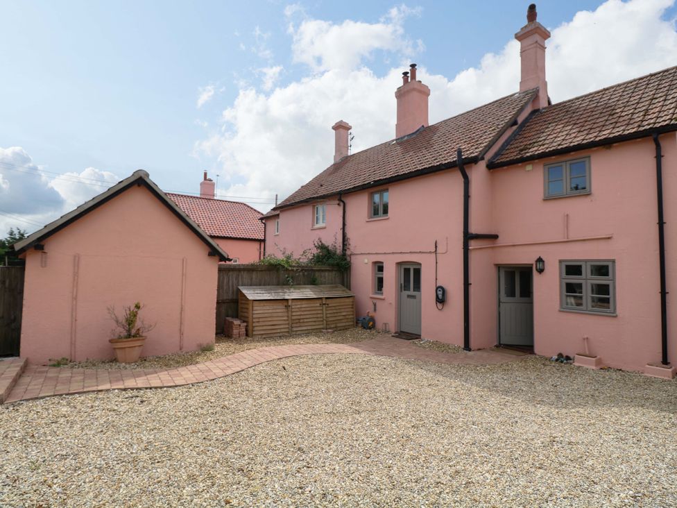 A garden area with a pink house and wooden shed at The Mallows in Walsingham